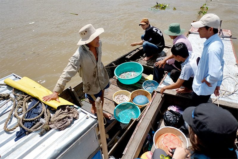 University researchers (right) buy fish for their survey from a local fisherman (left). 