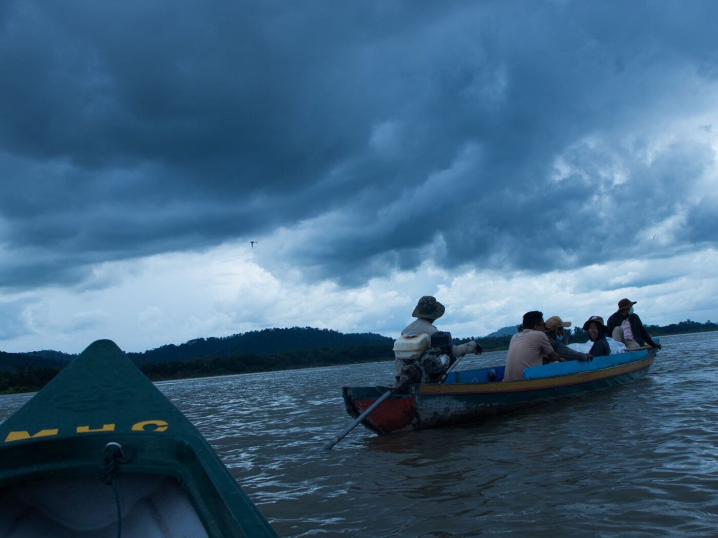 People in a small boat on water as a large storm brews