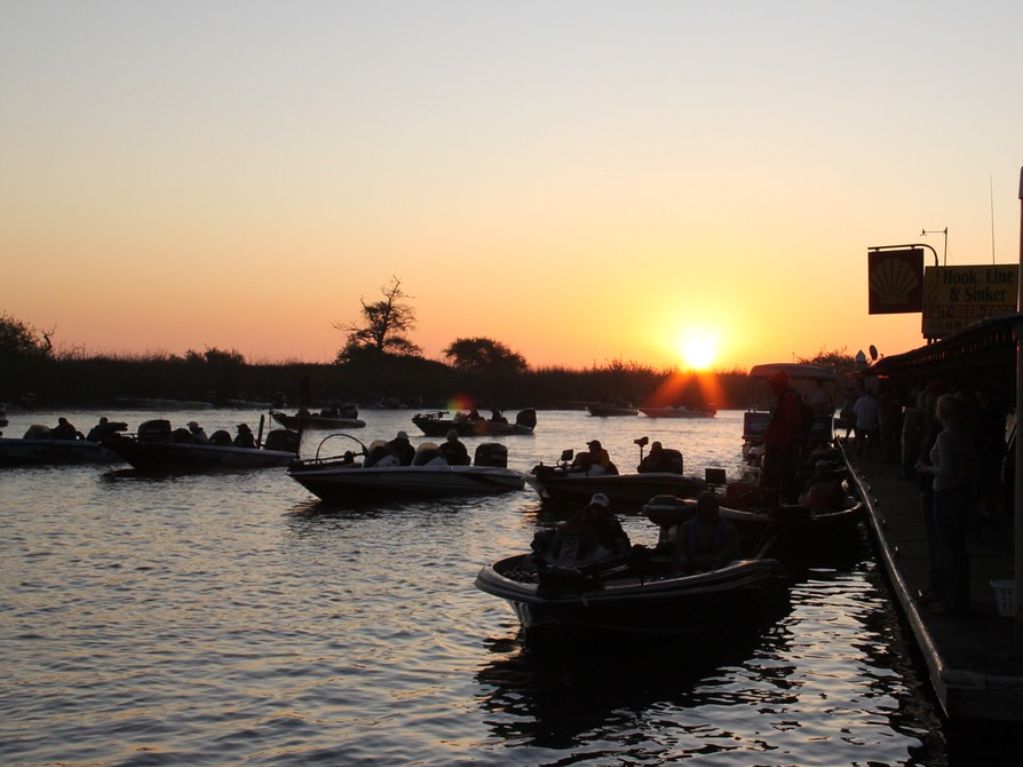 Several boats on water backlit by sunrise.